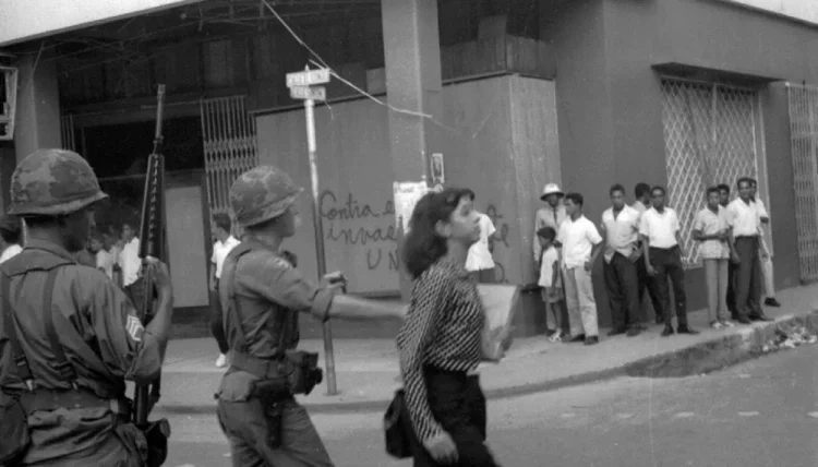 1965. Mujer es empujada por soldado norteamericano mientras caminaba por la calle. Foto Tomada del Caribe.